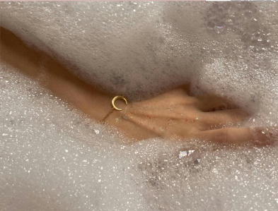 Hand mit Armband in Badewanne mit Schaum
