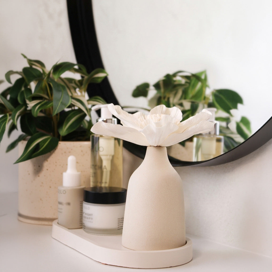 Blütendiffusor auf Dekotablett im Badezimmer neben Kosmetik