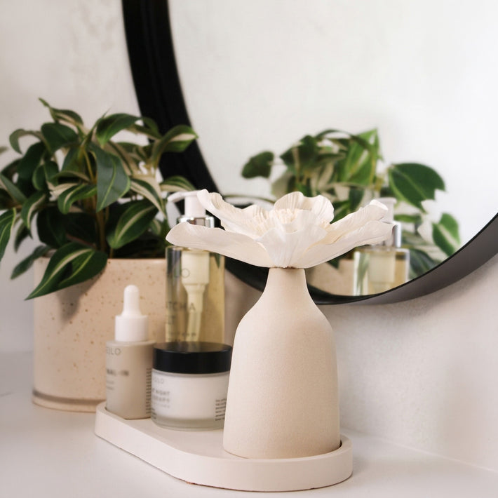 Blütendiffusor auf Dekotablett im Badezimmer neben Kosmetik