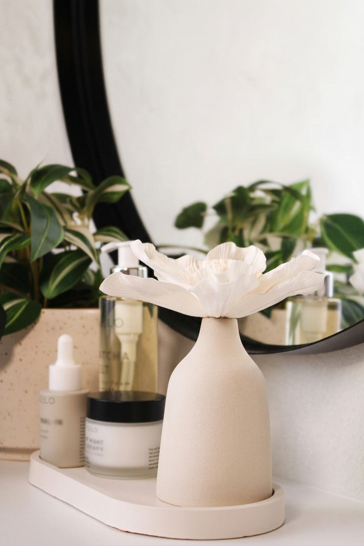 Blütendiffusor auf Dekotablett im Badezimmer neben Kosmetik