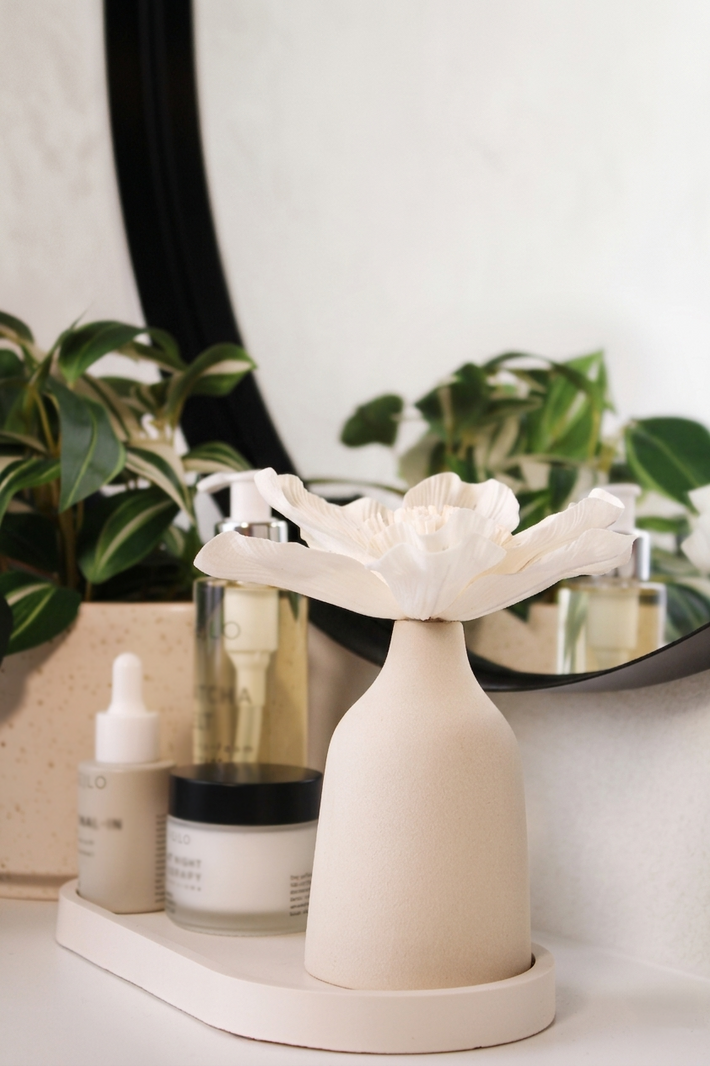 Blütendiffusor auf Dekotablett im Badezimmer neben Kosmetik