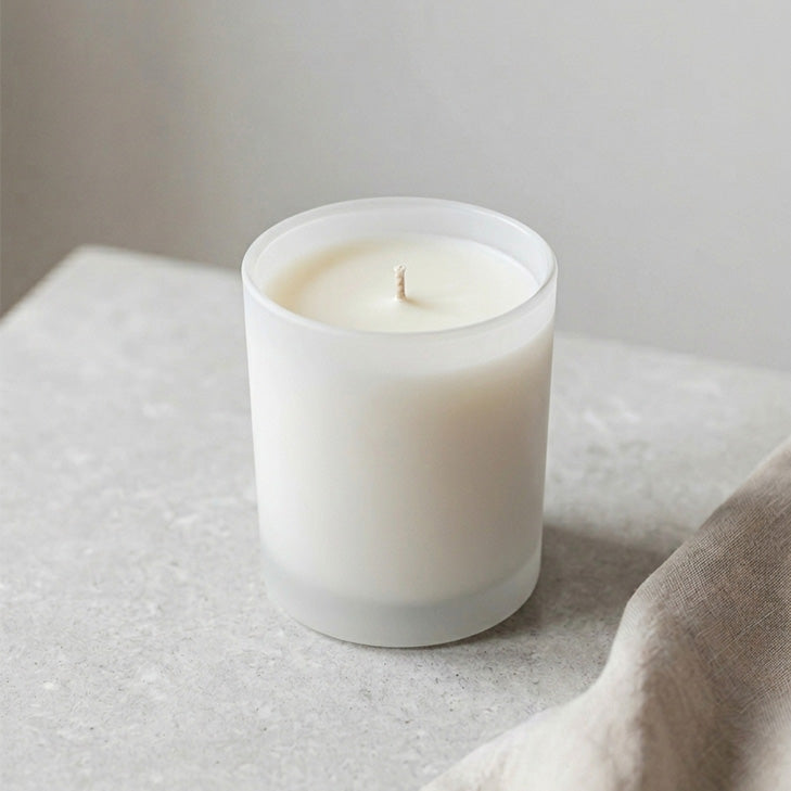 Mittelgroße Duftkerze mit cremefarbenem Wachs in milchweißem Glas im minimalistischen Design