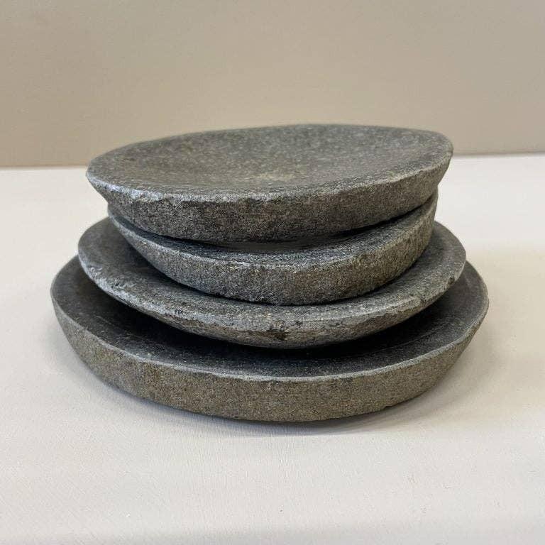 Vier dunkle Granitschalen aufeinander gestapelt vor minimalistischem Hintergund