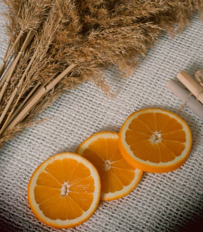 Frische Orangenscheiben auf Stoff neben getrocknetem Pampasgras