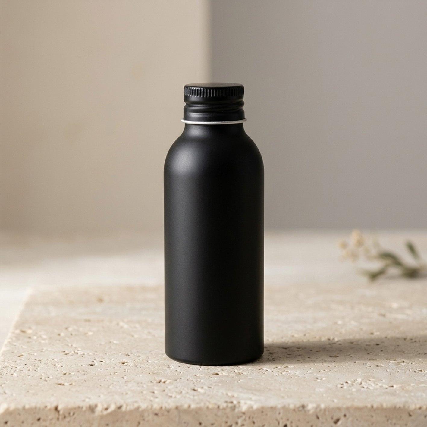Matte schwarze Flasche mit Duftessenz für Duftdiffusor vor minimalistischem Hintergrund