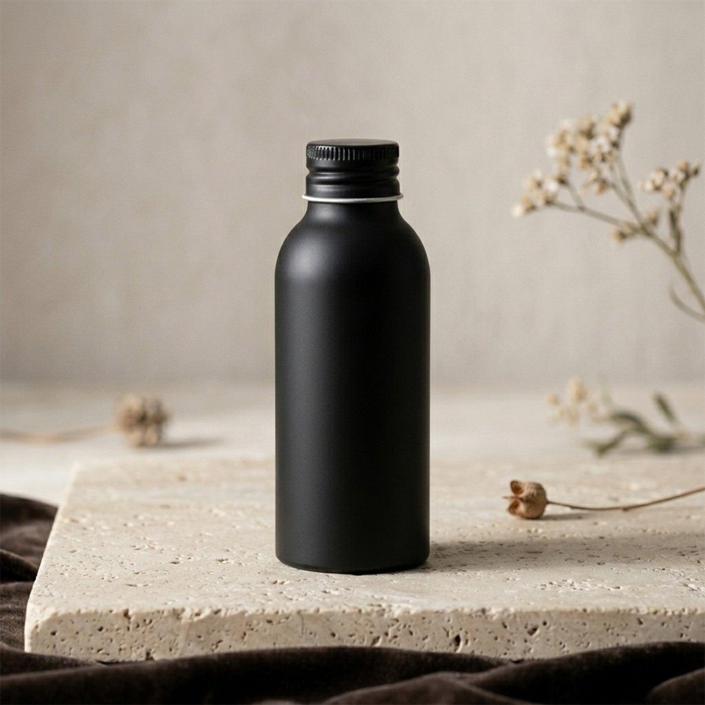 Matte schwarze Flasche mit Duftessenz für Duftdiffusor vor minimalistischem Hintergrund
