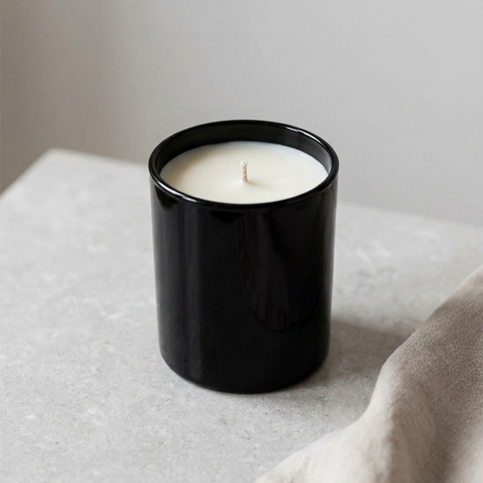 Mittelgroße Duftkerze mit cremefarbenem Wachs in schwarzem Glas im minimalistischen Design